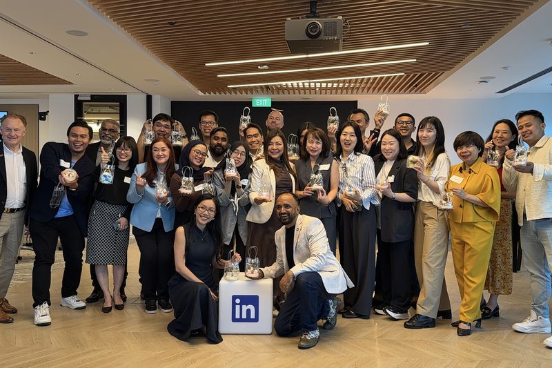 A large office team poses with the candles they made at a White Pixies workshop