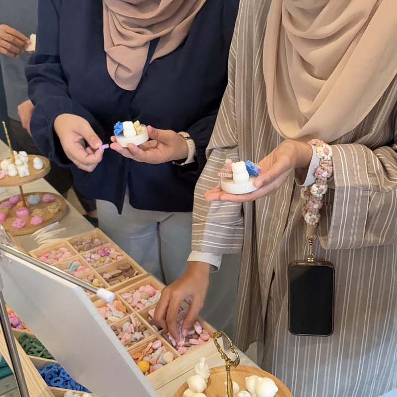 Guests hold up the small candles they decorated at a White Pixies candle station