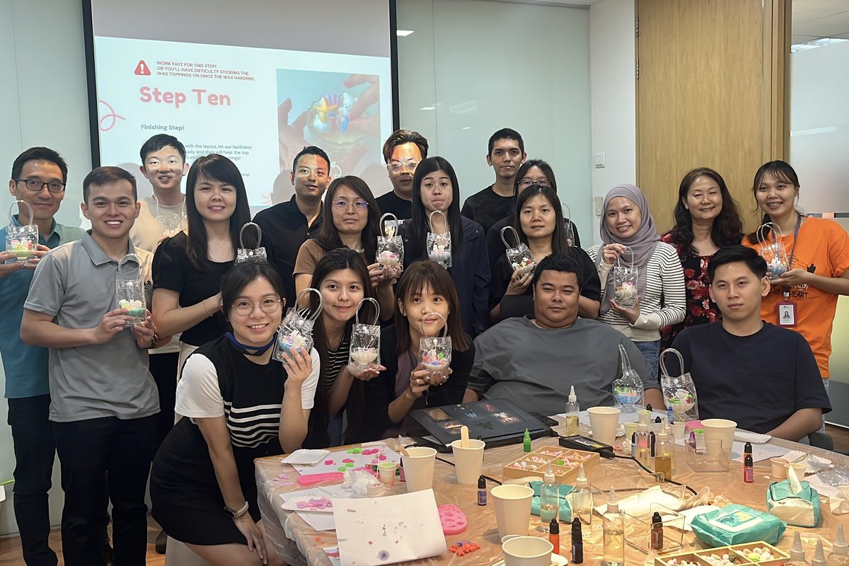 An office team holds up the candles they made at a White Pixies team building workshop