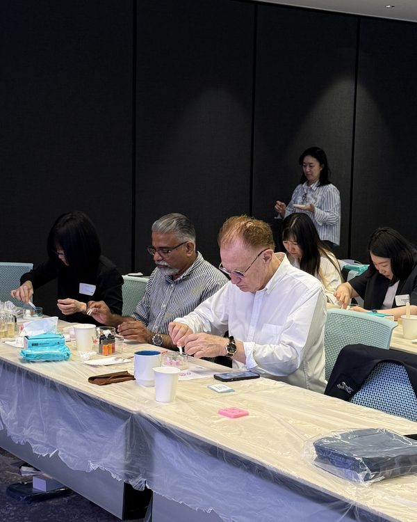 Colleagues make candles together at a long table during an office workshop