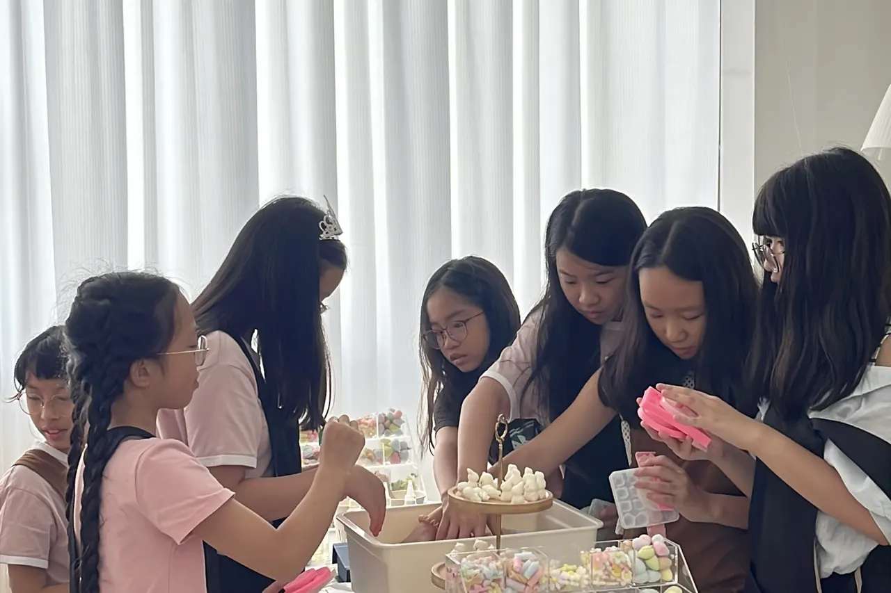 A child decorating a candle at a school holiday workshop in Singapore